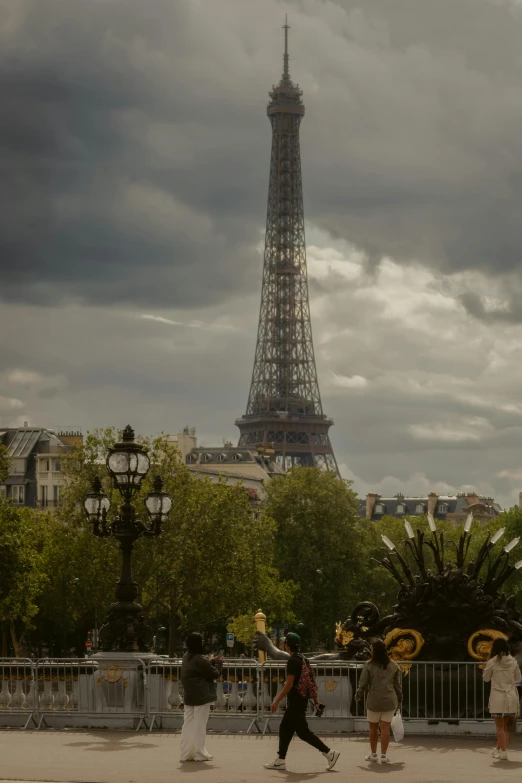 two women walk beside a large tower on a cloudy day