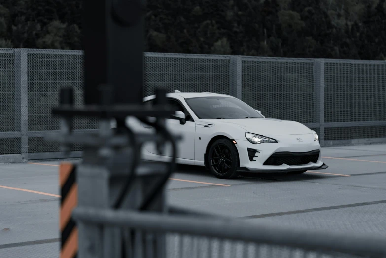 the front end of a white car in a parking lot