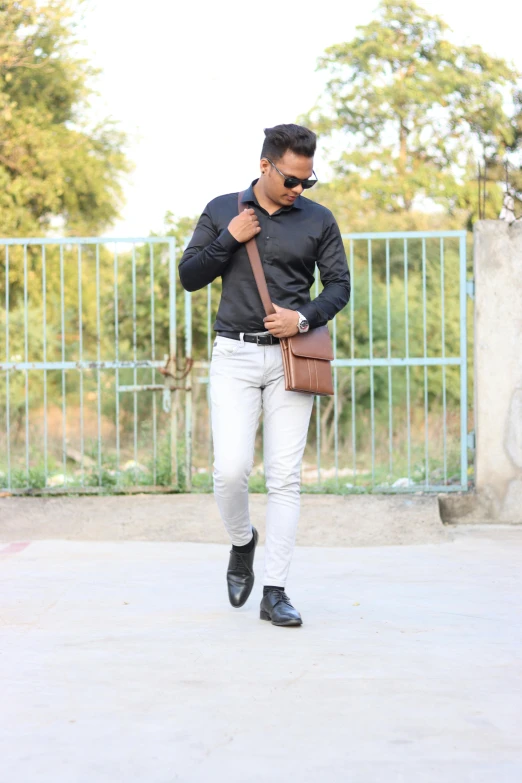 a man is holding a brown handbag and walking down the street