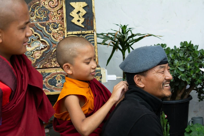 three young monks standing by a potted plant