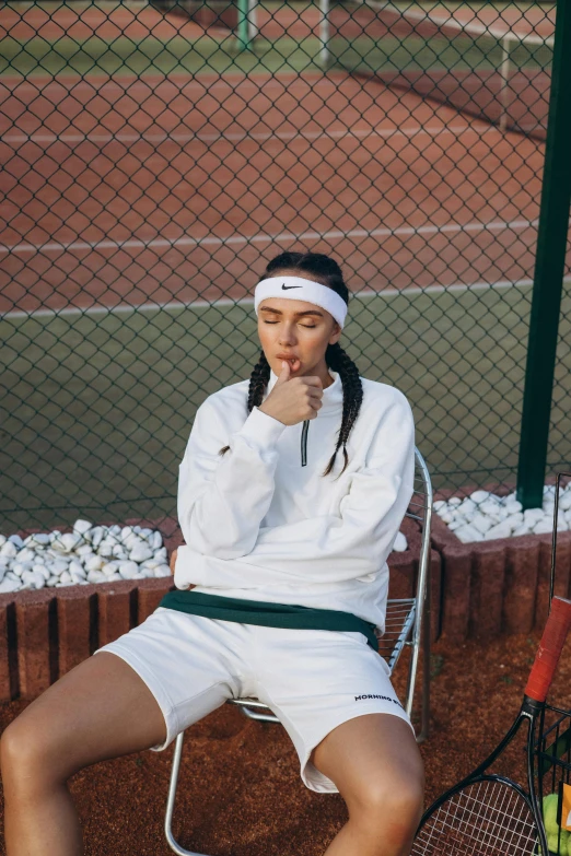 a woman sitting on a chair with a tennis racket and ball