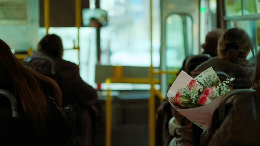 a close up of a person on a bus holding flowers