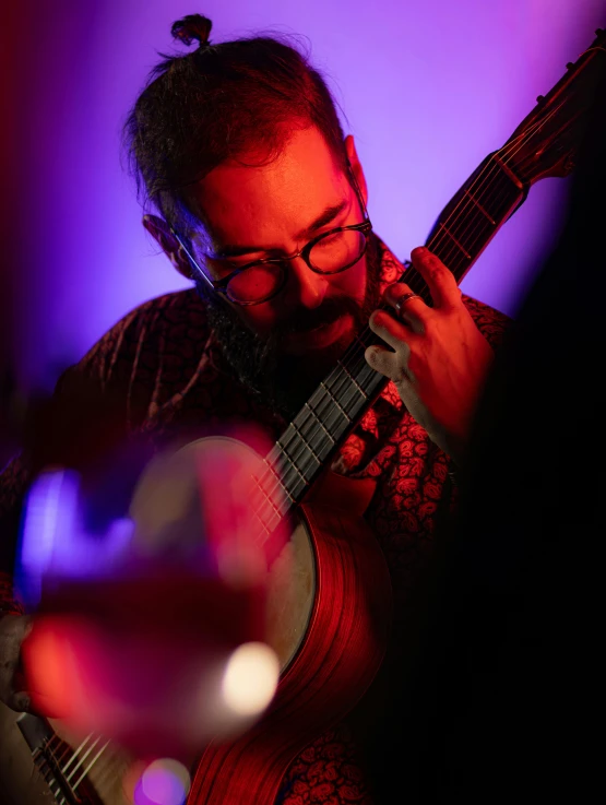 a man playing guitar while another person watches