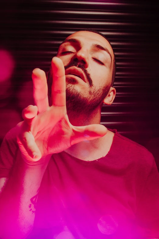 man holding his hand out in front of his face while looking up