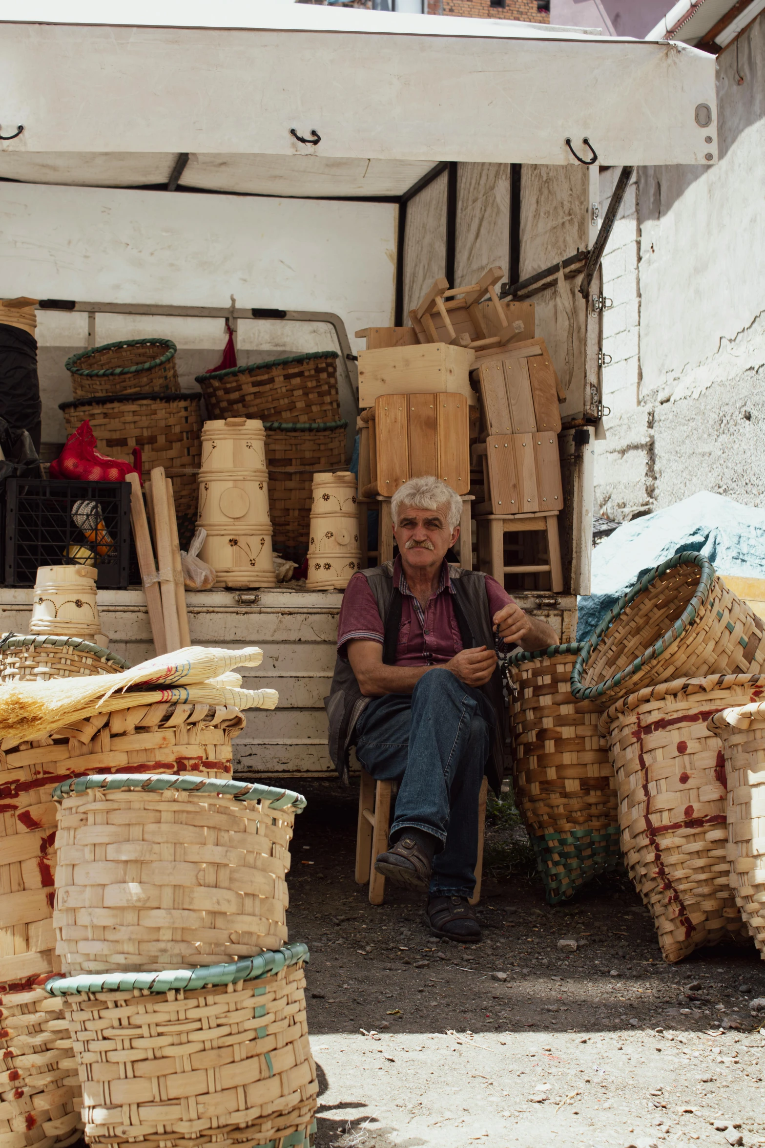 an older woman sits in front of stacked baskets