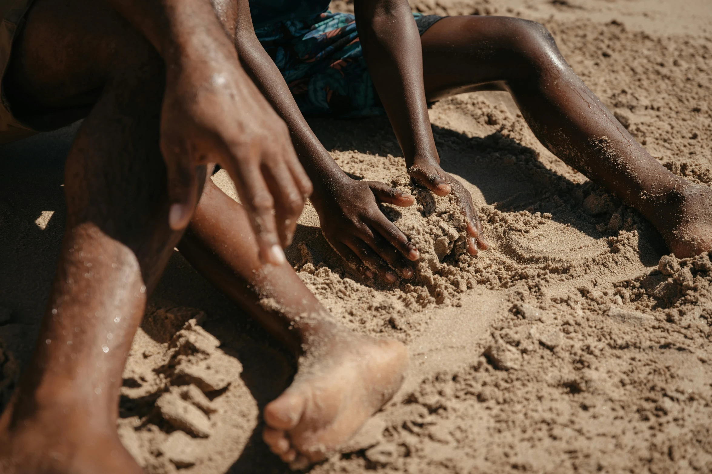 a man is sitting in the sand with his hands on his ankles