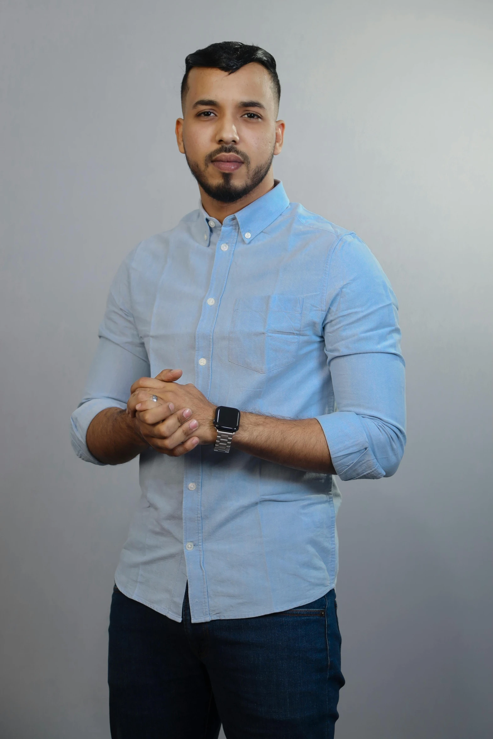 a young man is wearing a watch while standing with his hands together