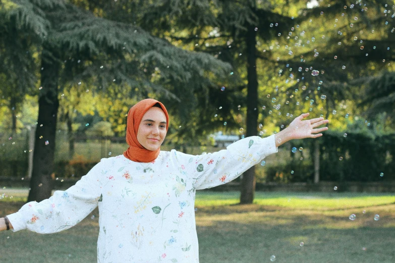 a woman wearing an orange headscarf is tossing bubbles