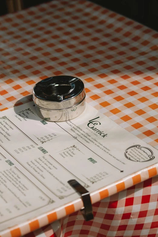 a table set with a checkered orange and white cloth and a compass on it