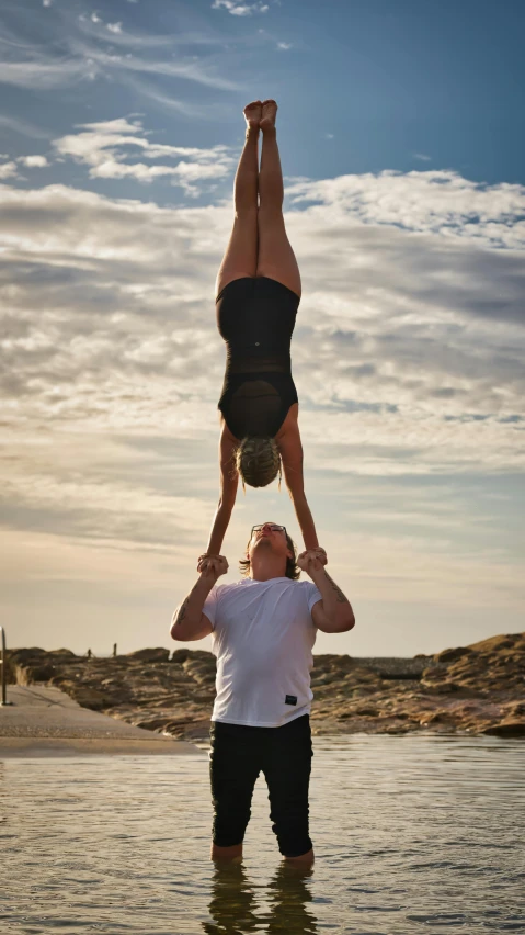 a man balancing on the back of a woman in water