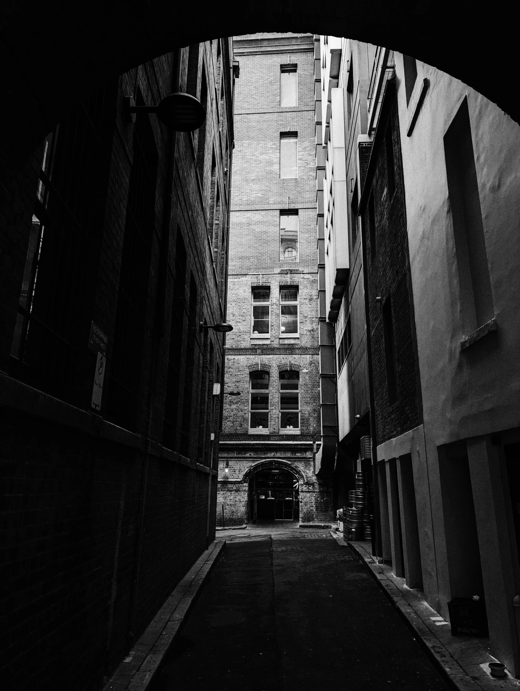 view from a dark alley into an old brick building