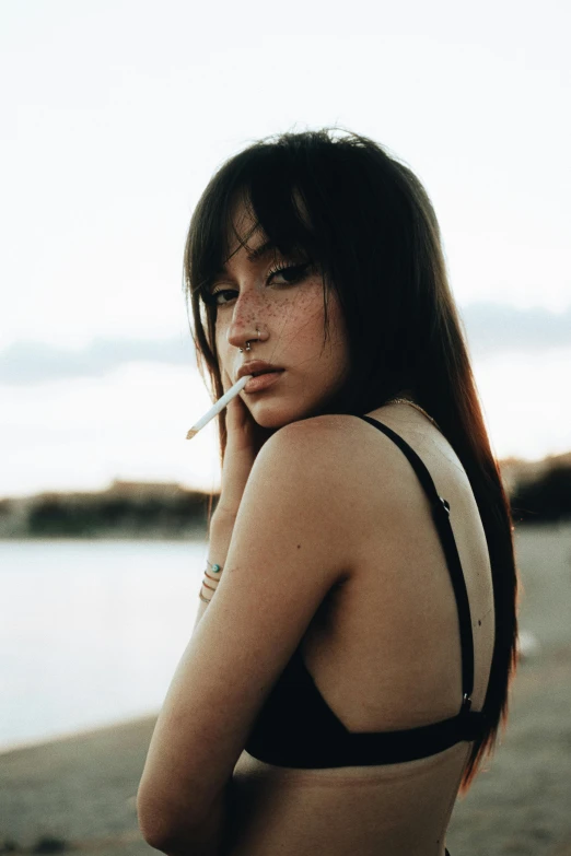 a woman wearing a bikini top and smoking a cigarette