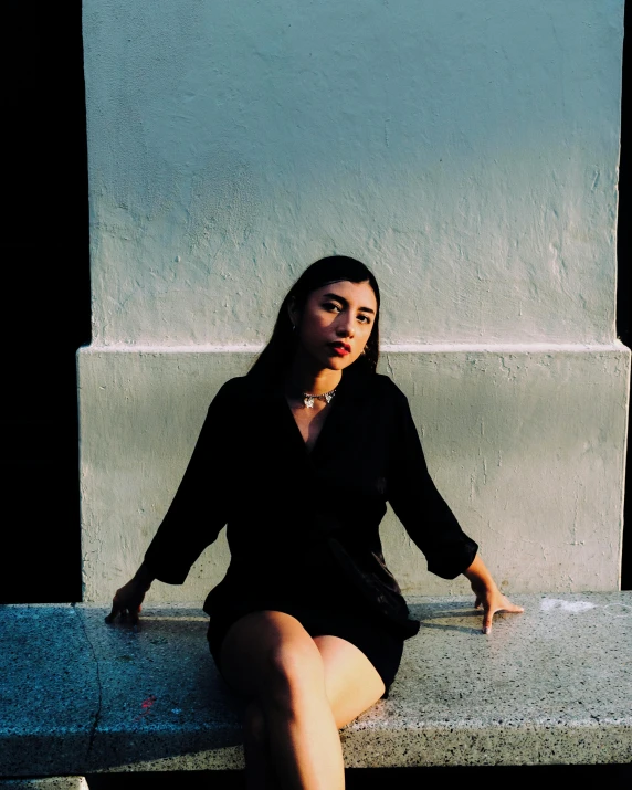 a woman wearing black sitting on top of a cement bench