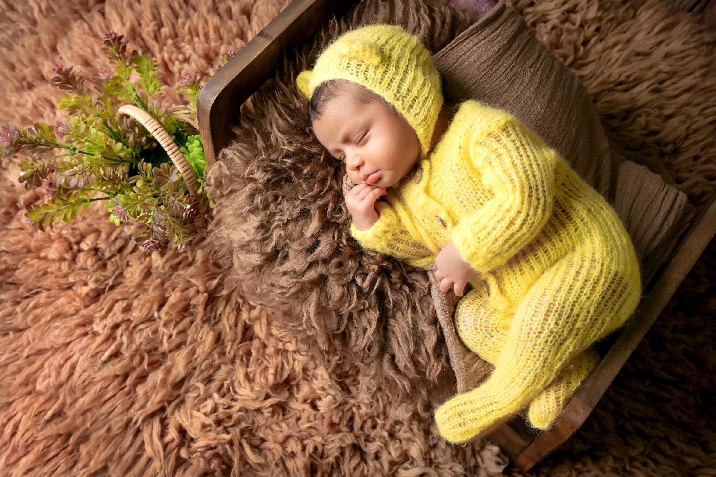 a baby is laying down next to a fake sheep