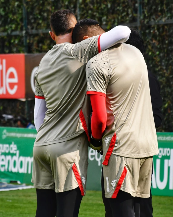 two men hug as they stand on a soccer field