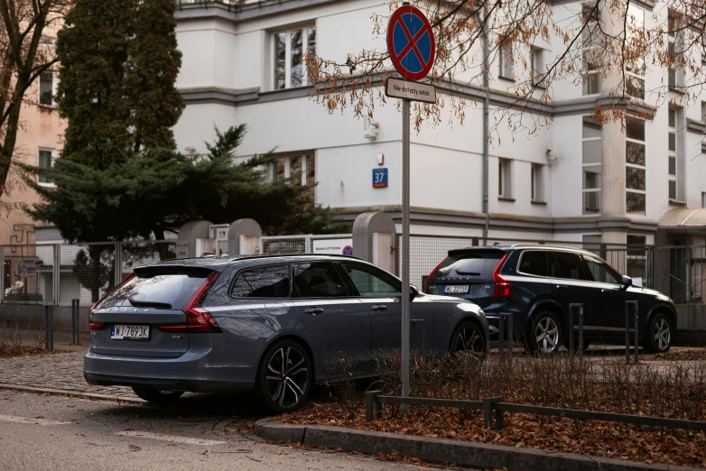 two black cars parked on the street beside an apartment complex