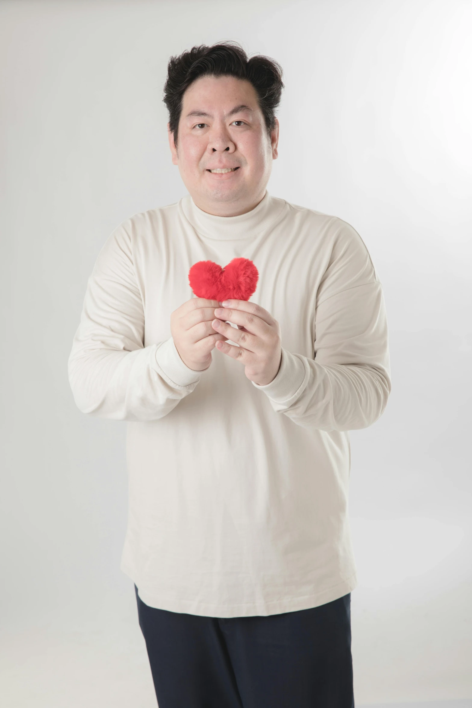 a guy wearing a turtle neck shirt holding two heart shaped pieces
