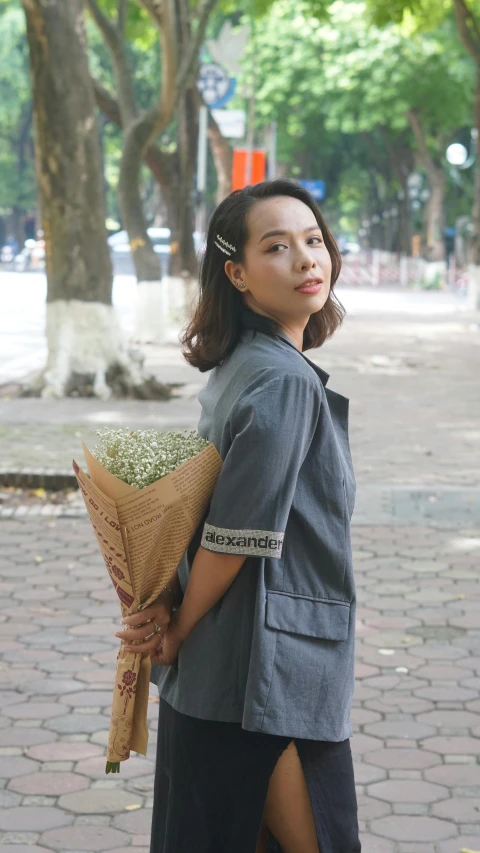 the young woman in the gray dress holds flowers