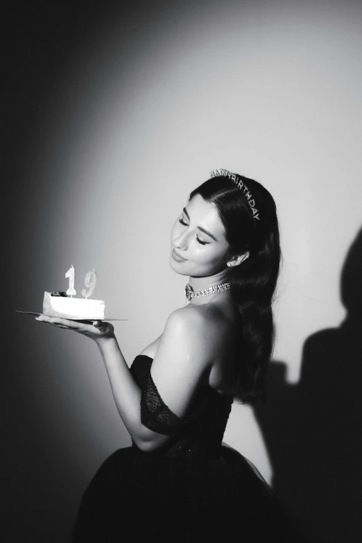 a woman in black dress holding cake with lit candles