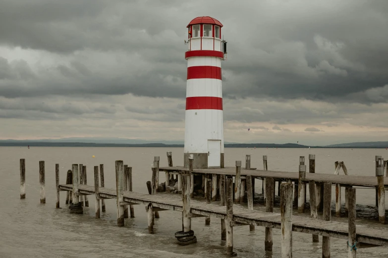 the light house is on the water with a pier