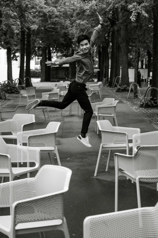 a young man jumping in the air over a pile of chairs