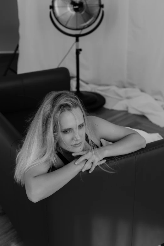 a woman laying on top of a black leather couch