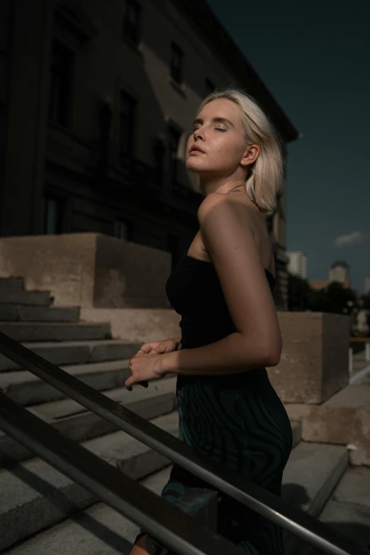 a woman with blonde hair standing in front of stairs