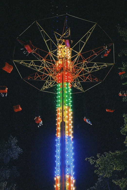 a colorful fair ride in the dark with people riding on it