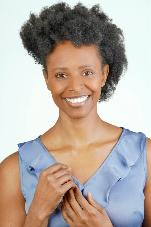 a smiling african woman in a blue shirt is holding her hands together