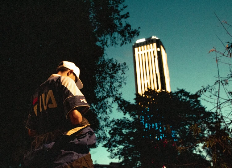 a man standing by some tall building while talking on a cellphone