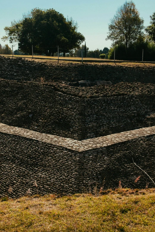 a bench is in the foreground of a stone wall