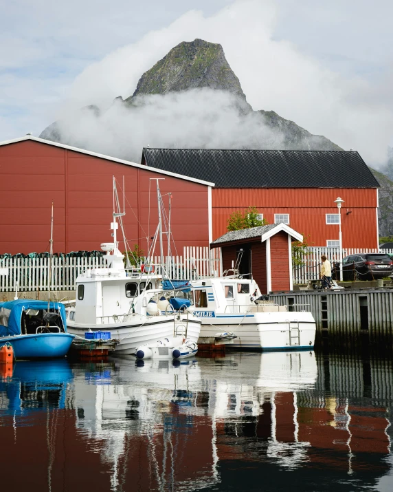 the boats are in front of the large red barn