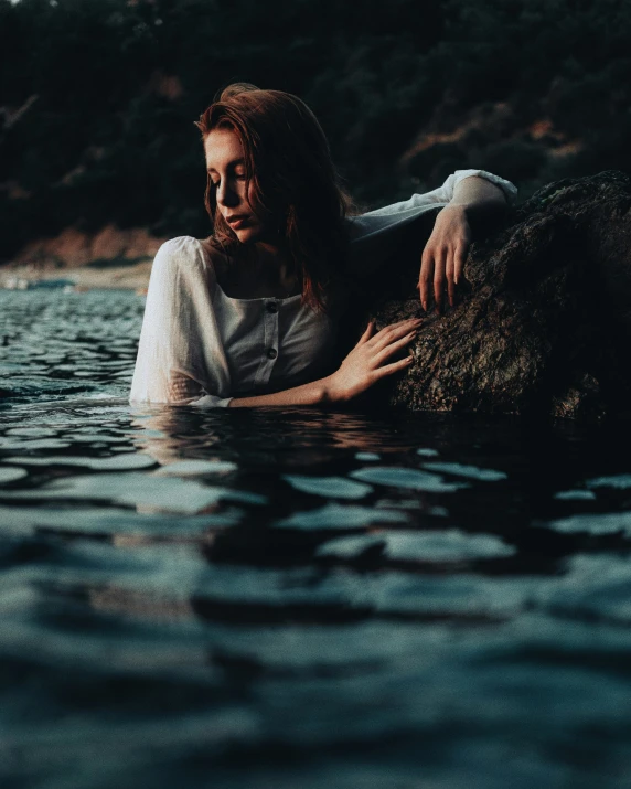 woman in water looking to camera with hand on body of water