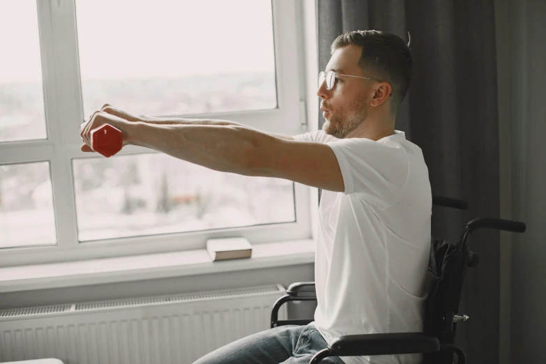 man in a wheelchair holding a red cup to his forehead