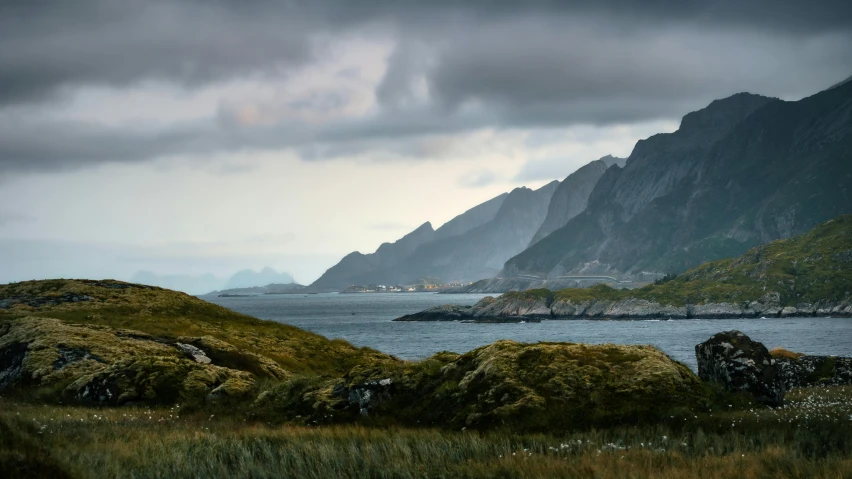 view of mountains, grass and ocean in foreground