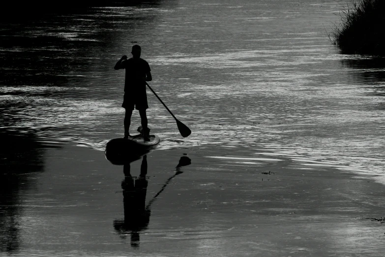 a man stands in a canoe on the edge of the river while holding a paddle