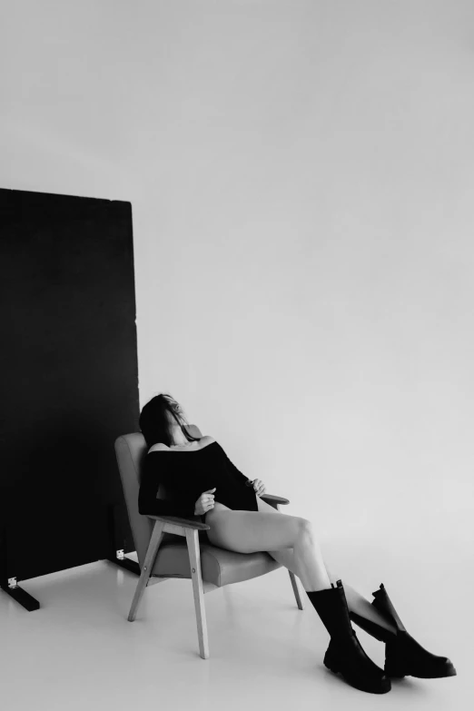 black and white image of a woman in chair, with feet crossed