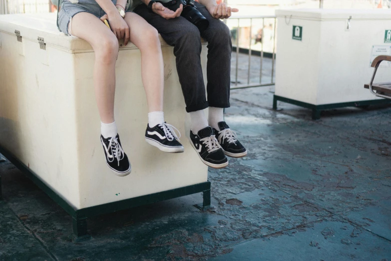 two people sit on top of a bench and drink water