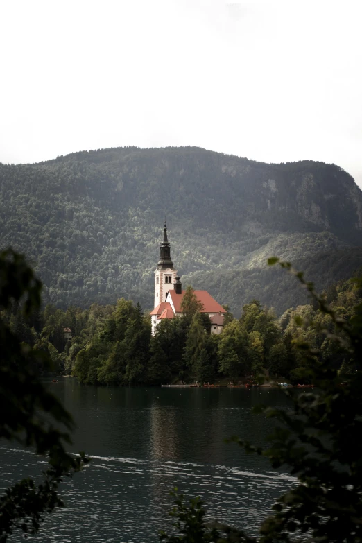 a church surrounded by trees sitting on the shore