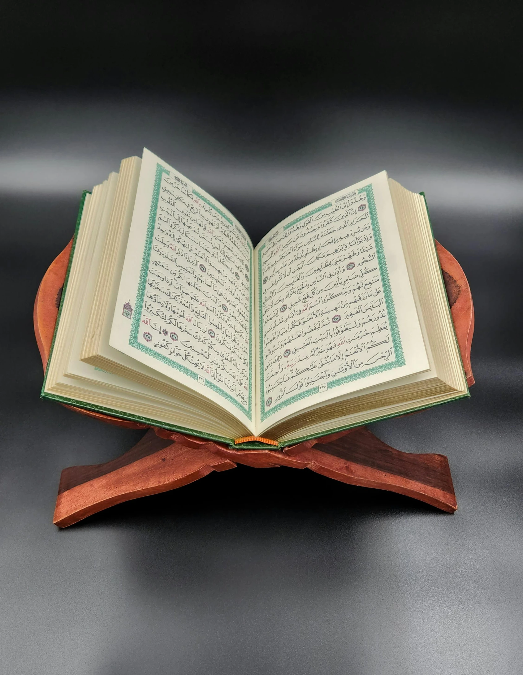 an open islamic book sitting on top of a wooden stand