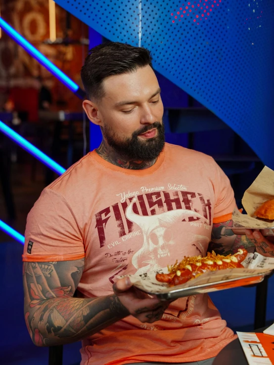 a tattooed man with tattoos holding food in his hands