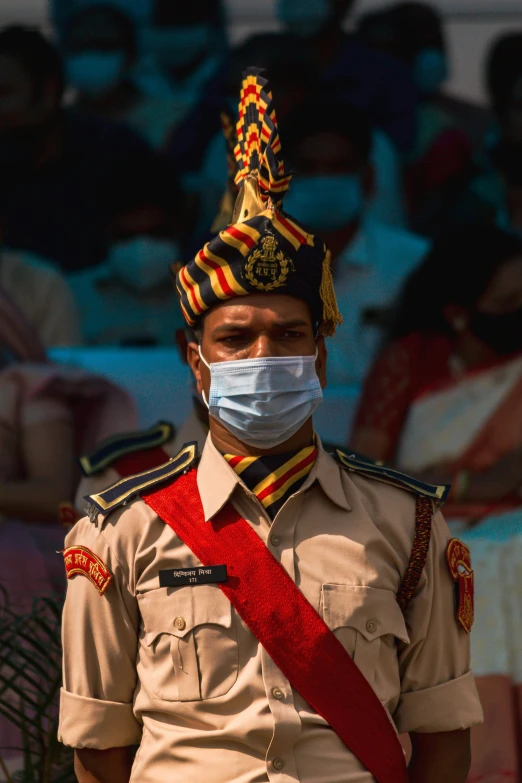 a military guard wearing a face mask, and other people in the background