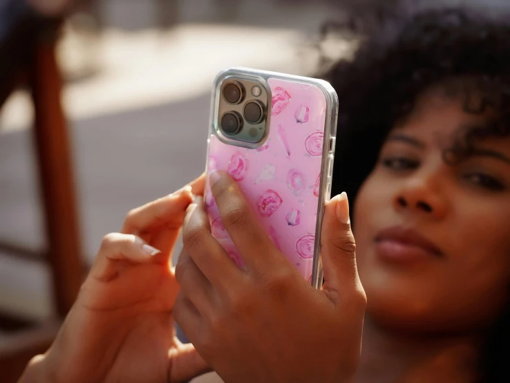 a person wearing a pink iphone case holding a camera phone