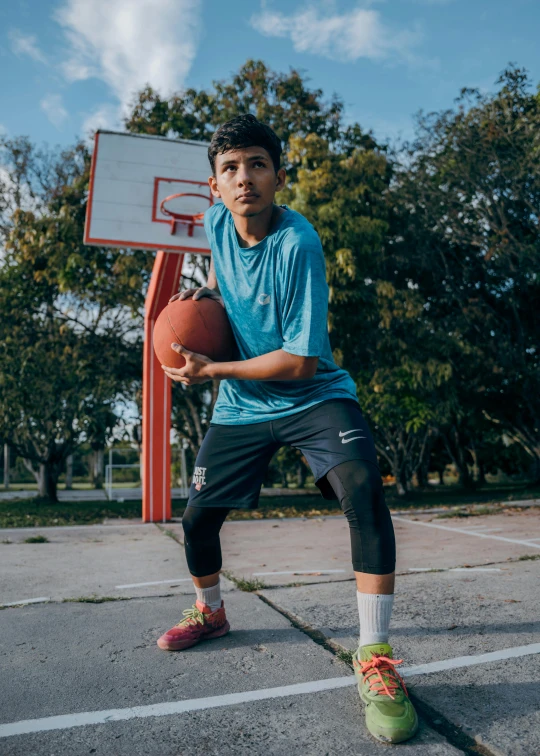 a boy in a blue shirt is holding a basketball