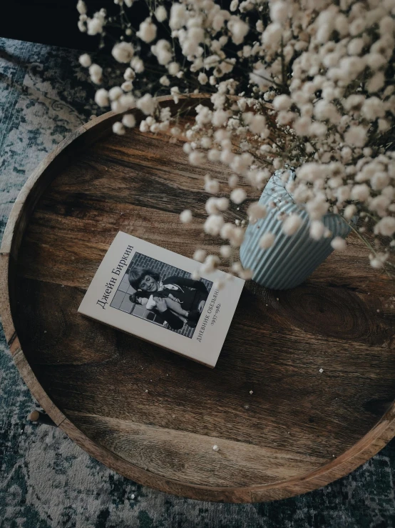 an old wooden tray holding a vase and small book