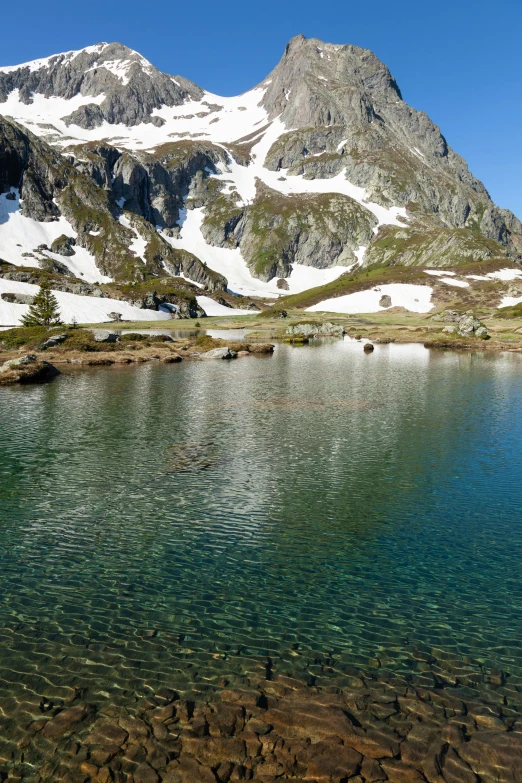 a snowy mountain is next to a clear lake