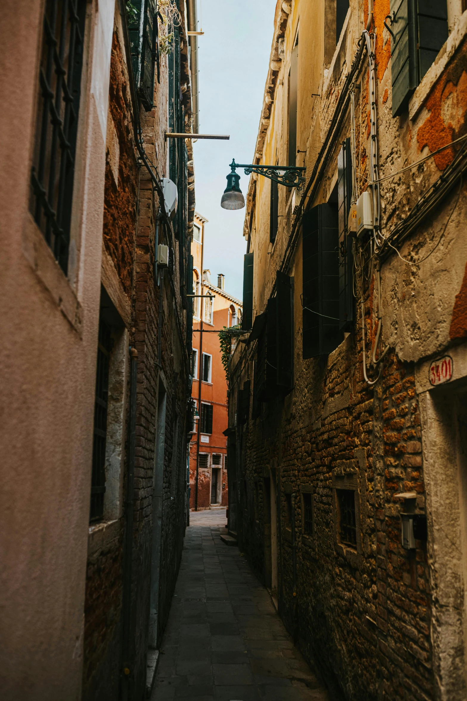 a narrow city street with an overhanging lamp