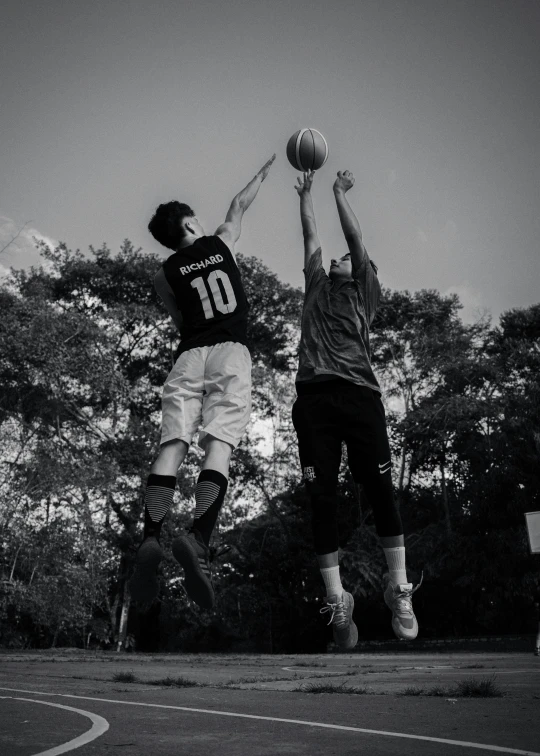 two men jumping in the air with basketball