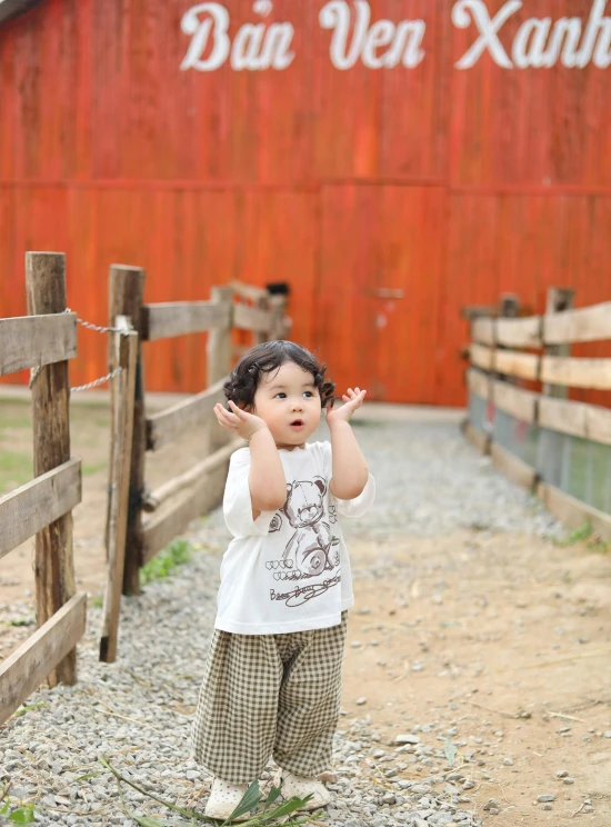 a child in pajamas is standing near a barn