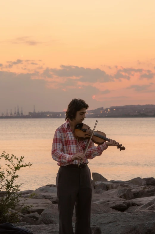 a man playing a violin by the water